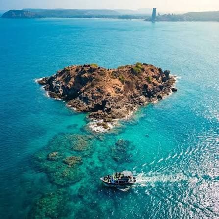 Netrani Island in the Arabian Sea, a rocky islet with a boat approaching through clear water